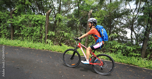 Woman cyclist riding mountain bike on tropical rainforest trail
