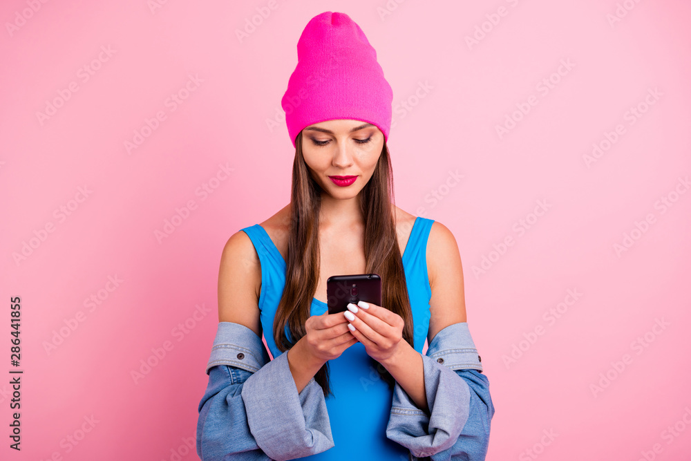 Portrait of concentrated woman holding device wearing blue bodysuit isolated over pink background Portrait of concentrated woman holding device wearing blue bodysuit isolated over pink background