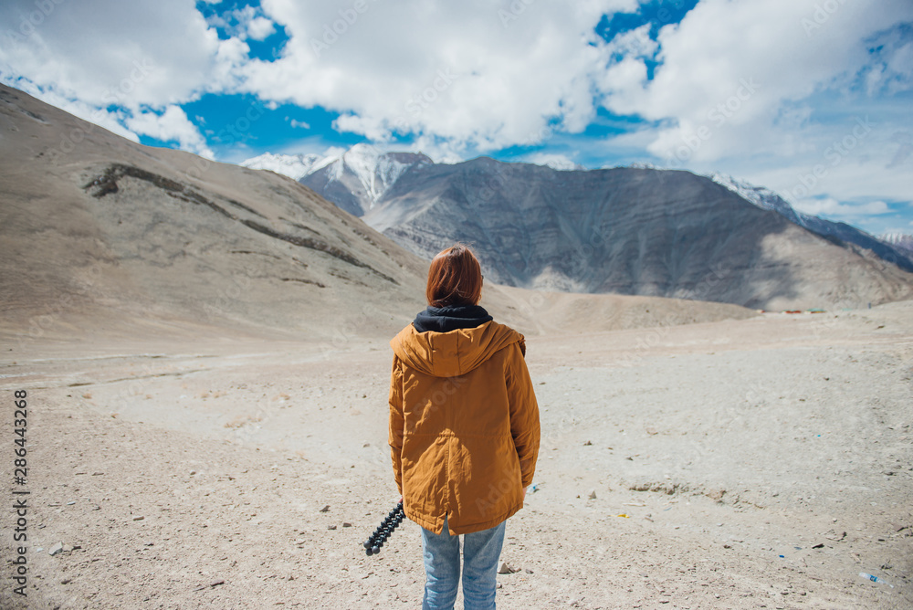 Happy woman traveler in yellow jacket enjoy the beautiful view at mountain in Leh Ladakh, India. Freedom and happiness concept. Happy woman traveler in yellow jacket enjoy the beautiful view at mountain in Leh Ladakh, India. Freedom and happiness concept.