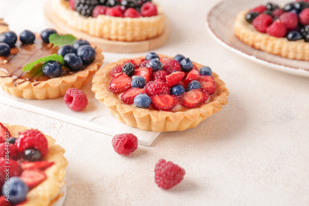 Sweet tartlets with berries on light table Sweet tartlets with berries on light table