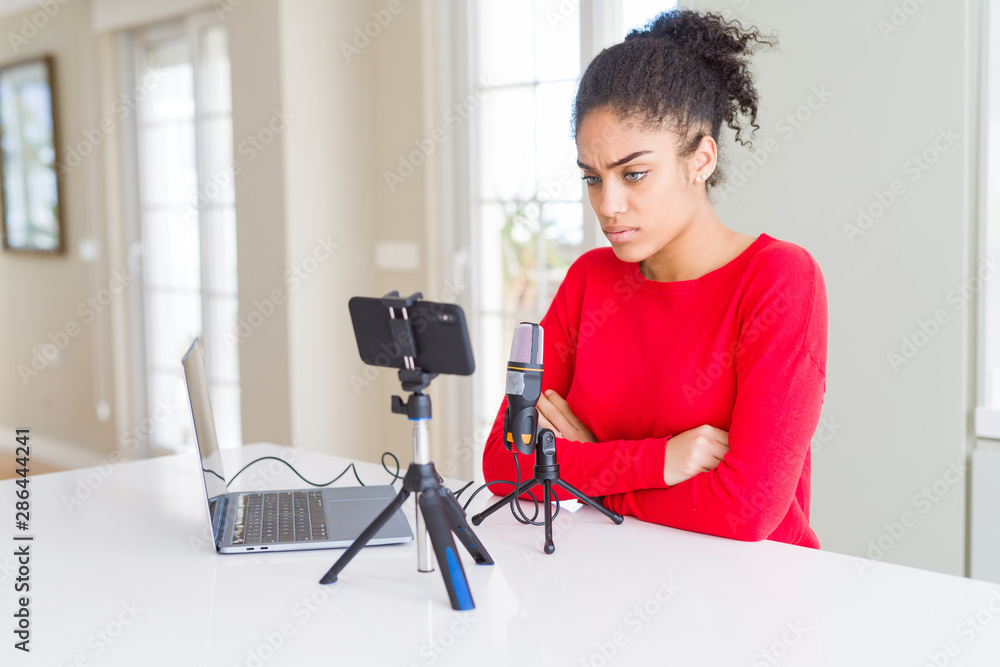 Young african american woman doing video call using smartphone camera and microphone skeptic and nervous, disapproving expression on face with crossed arms. Negative person. Young african american woman doing video call using smartphone camera and microphone skeptic and nervous, disapproving expression on face with crossed arms. Negative person.