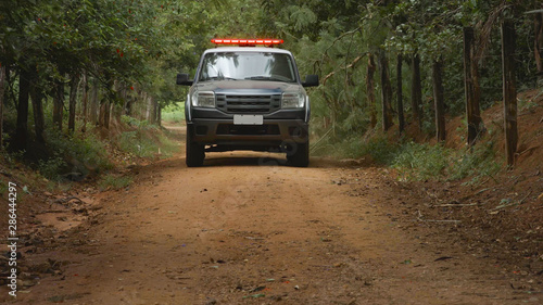 forest police car on a dirt road surrounded by fence and trees