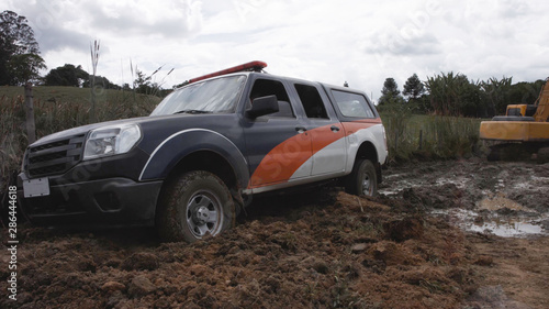 police car stuck in a mud road on a farm in the afternoon with cloudy sky - Image © Thiago Melo