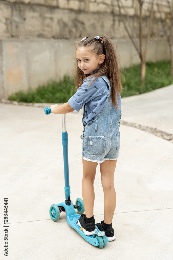 Naklejka premium Back view of girl with blue scooter