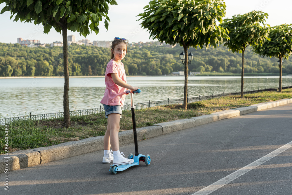 Naklejka premium Back view of girl riding blue scooter
