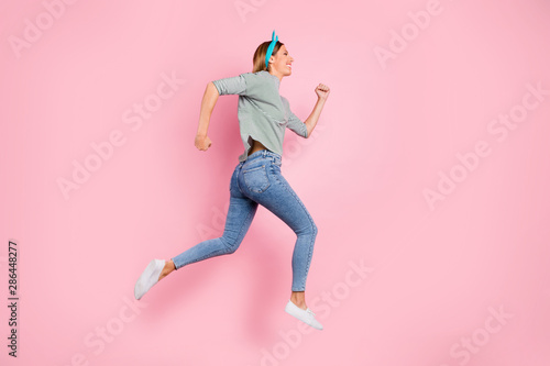 Full length body size profile side view of her she nice-looking attractive charming lovely cheerful cheery straight-haired girl running fast isolated over pink pastel background