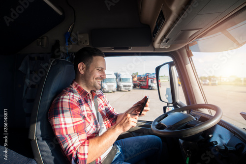 Truck driver sitting in his cabin and getting coordinates directions with tablet using GPS navigation for his route. Transportation services. photo