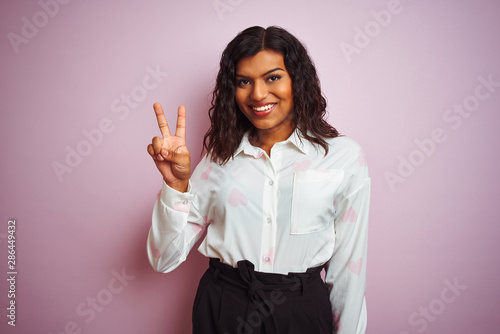 Transsexual transgender businesswoman standing over isolated pink background showing and pointing up with fingers number two while smiling confident and happy. photo