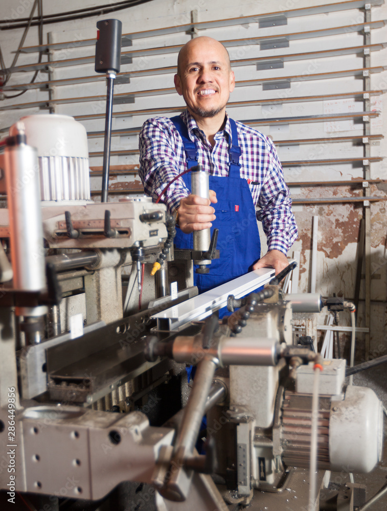 middle age smiling worker at professional lathe in plant