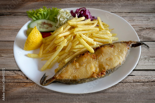 Fried fish - halibut, salad and french fries on plate