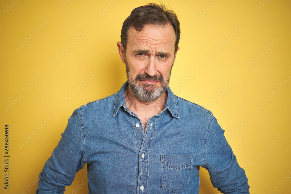 Handsome middle age senior man with grey hair over isolated yellow background depressed and worry for distress, crying angry and afraid. Sad expression. Handsome middle age senior man with grey hair over isolated yellow background depressed and worry for distress, crying angry and afraid. Sad expression.