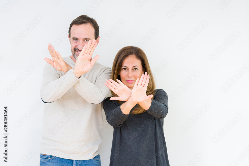 Beautiful middle age couple in love over isolated background Rejection expression crossing arms and palms doing negative sign, angry face Beautiful middle age couple in love over isolated background Rejection expression crossing arms and palms doing negative sign, angry face