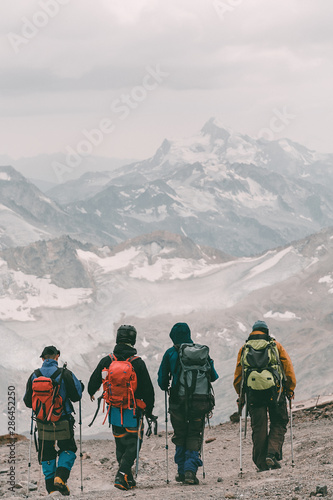 Hiking and climbing. Four tourists with backpacks on the background of a mountain snow-covered ridge