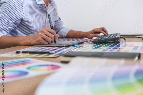 Wallpaper Mural Image of male creative graphic designer working on color selection and drawing on graphics tablet at workplace with work tools and accessories in workspace Torontodigital.ca