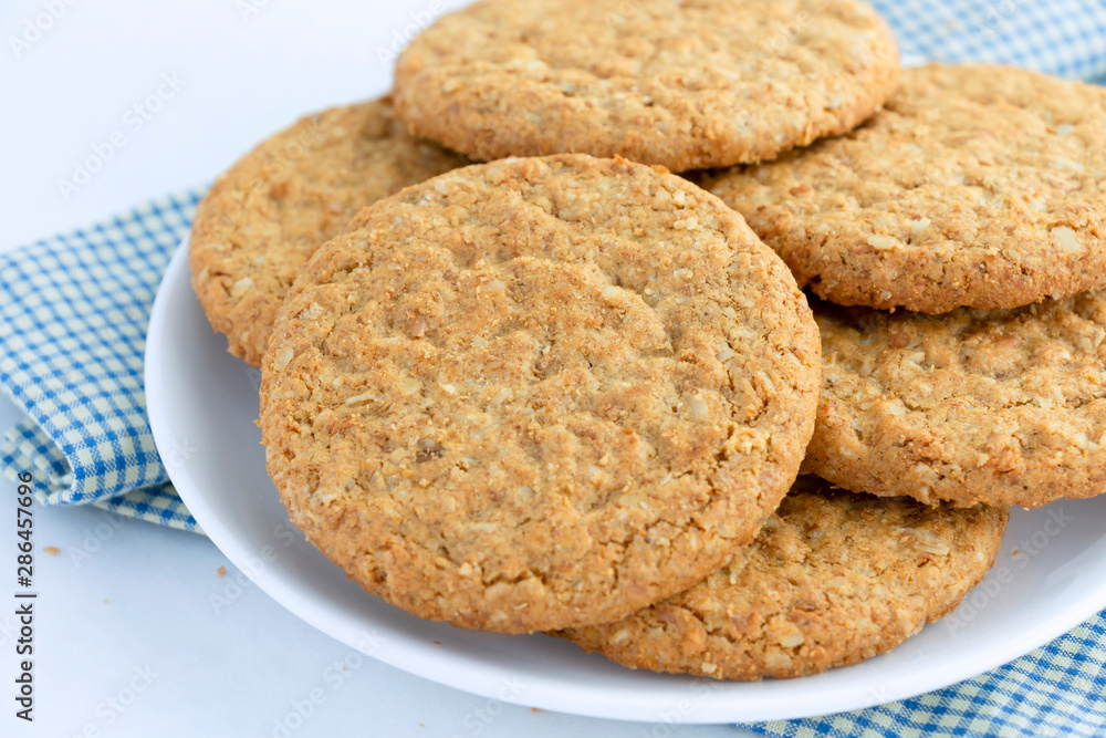 Homemade shortbread cookies made of oatmeal are pile on white plate on the cloth background. Concept food healthy snack for enjoy in holiday. Homemade shortbread cookies made of oatmeal are pile on white plate on the cloth background. Concept food healthy snack for enjoy in holiday.
