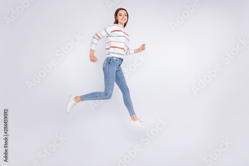 Full length photo of lovely youth running smiling wearing striped jumper isolated over white background © deagreez