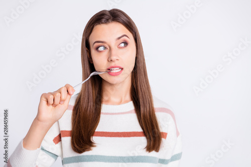 Hungry lady holding spoon into mouth want to know what is on supper wear striped pullover isolated white background