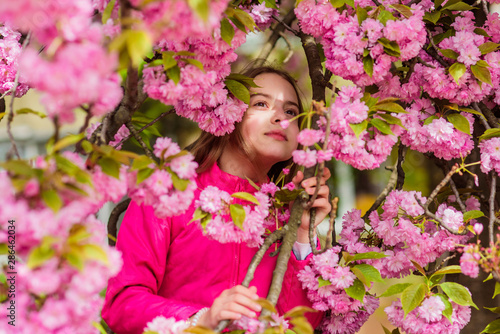 Girl enjoying floral aroma. Pollen allergy concept. Kid enjoy cherry blossom sakura. Kid on pink flowers sakura tree background. Child enjoy life without allergy. Allergy remedy. Sniffing flowers