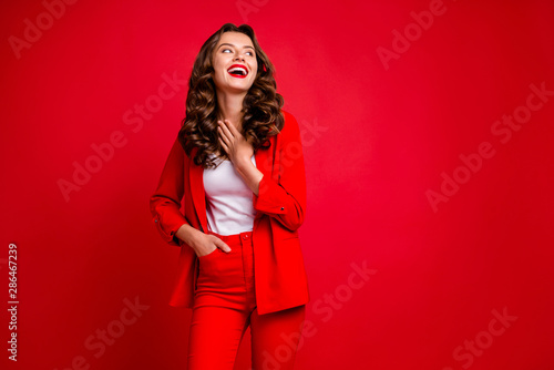 Portrait of lovely lady touching her chest looking up isolated over red background © deagreez
