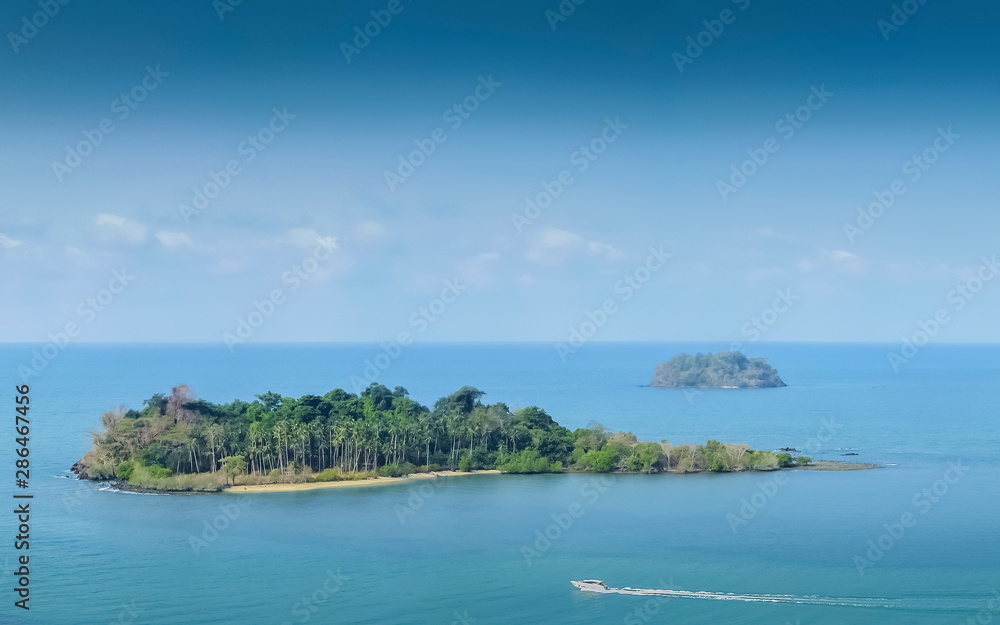 Top view above green forest of small island and a boat running in blue-green sea with blue sky background, Kai Bae View Point, Koh Chang Island, Trat, Thailand.