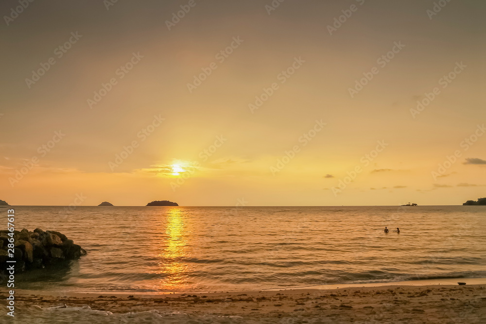 view seaside evening of small island and a small boat floating in the sea with yellow sun light in the sky background, sunset at Kai Bae Beach, Koh Chang Island, Trat,land.
