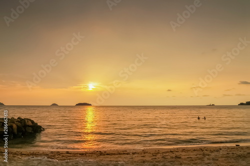 view seaside evening of small island and a small boat floating in the sea with yellow sun light in the sky background, sunset at Kai Bae Beach, Koh Chang Island, Trat,land.
