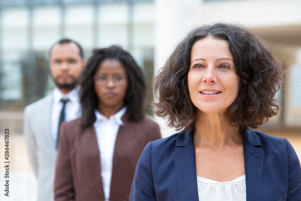 Female boss with multiethnic colleagues. Portrait of smiling middle aged businesswoman standing with male and female coworkers. Teamwork concept Female boss with multiethnic colleagues. Portrait of smiling middle aged businesswoman standing with male and female coworkers. Teamwork concept