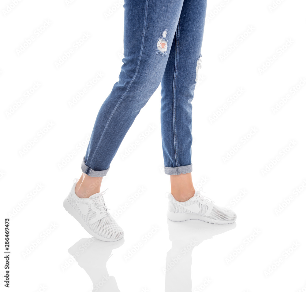 Legs in jeans and white sneakers isolated on a white background. Legs in jeans and white sneakers isolated on a white background.