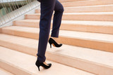 Cropped shot of businesswoman on stairs. Low section of woman in stylish black high-heeled shoes and formal wear walking on steps. Style concept