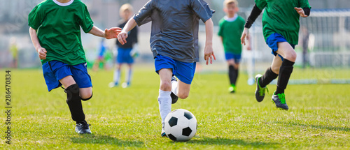 Boy Kicking Soccer Ball. Running Soccer Football Players. Five Junior Footballers on Duel. Football Grass Field and Soccer Stadium in the Background. © matimix