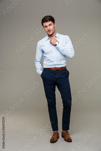 Image of confident young man wearing wristwatch poising at camera with hands in pocket photo