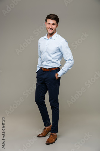Vászonkép Image of happy young man wearing formal clothes smiling at camera with hands in
