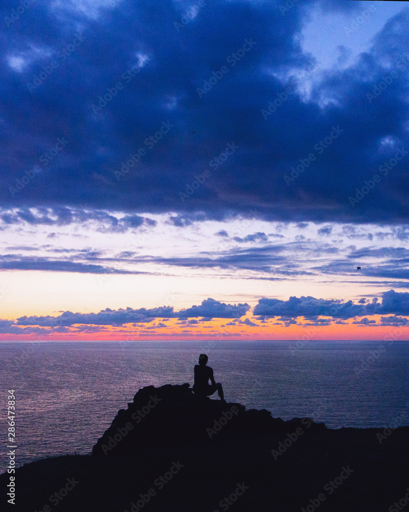 una persona sola quarda il tramonto al mare