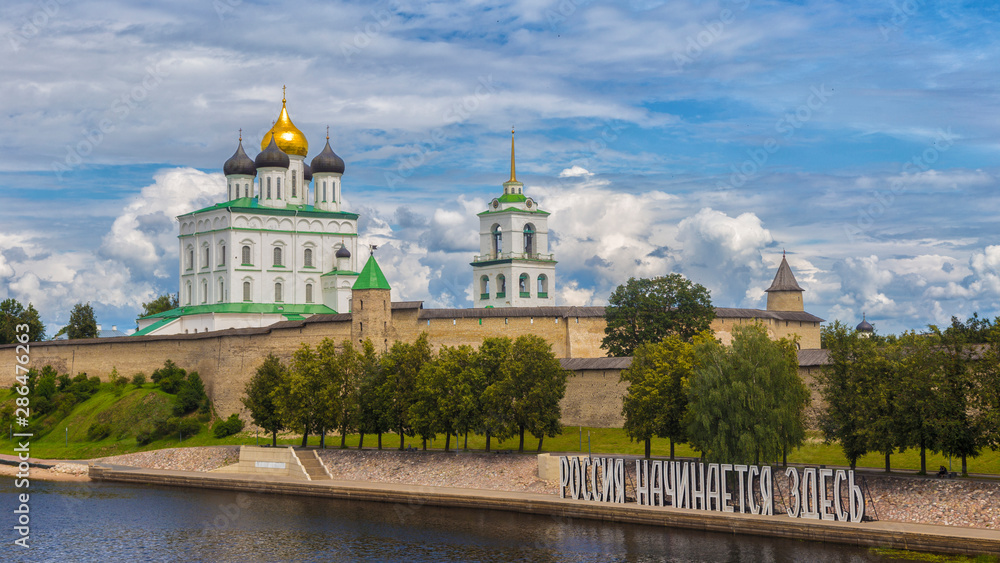 Kremlin in Pskov, Russia. Ancient fortress. Golden dome of Trinity Church. On the bank of the river the Great inscription in Russian 