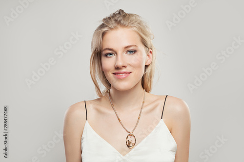 Portrait of beautiful blonde woman in fashion necklace on white background