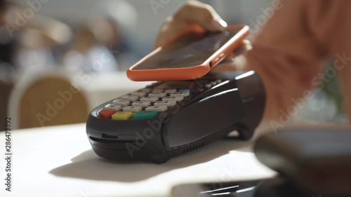 Close up hands woman paying in the cafe by credit card swiping with credit card on pos payment terminal on table in sunlight customer machine money terminal cash client electronic slow motion