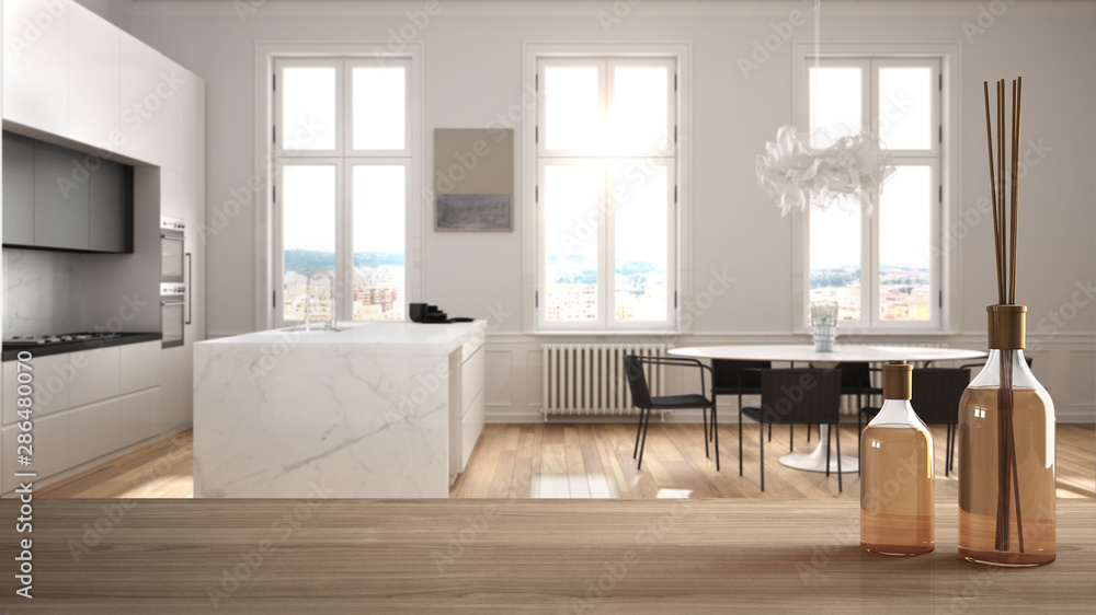 Fototapeta premium Wooden table top or shelf with aromatic sticks bottles over blurred modern white kitchen with parquet floor and dining table, white architecture interior design