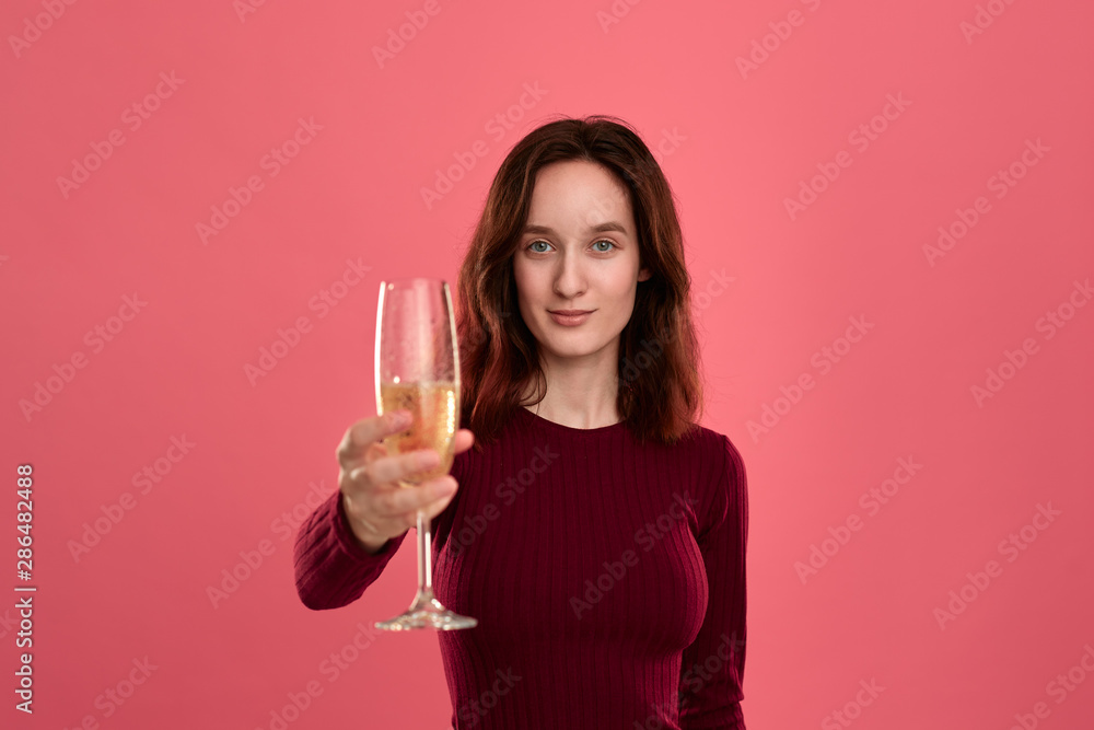 Excited pretty brunette girl holding wineglass of sparkling champagne standing isolated on a dark pink background and smiling at the camera. Excited pretty brunette girl holding wineglass of sparkling champagne standing isolated on a dark pink background and smiling at the camera.