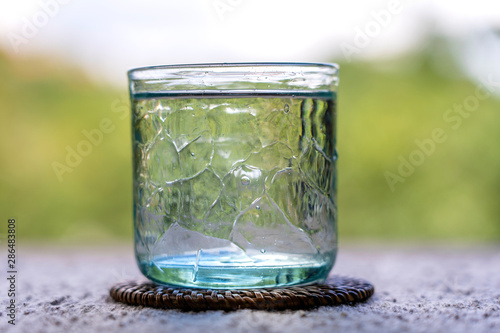Glass with cool fresh water on a table outdoors, closeup