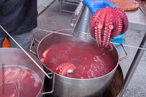 Pulpeiro enseñando tentáculos de pulpo a un cliente en la feria. photo