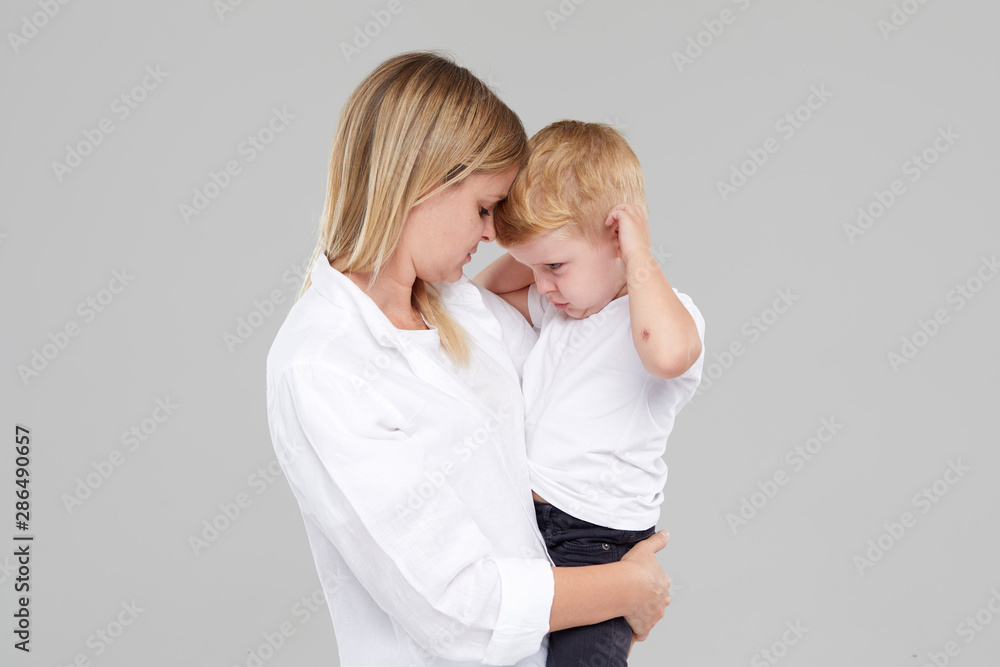 Young mother holding her crying child boy in her arms. The son is ill
