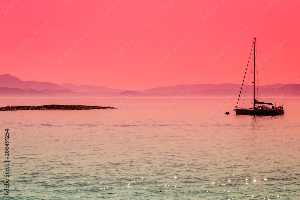 Peaceful, calming image of a yacht, moored off an island in the Inner Hebrides, Scotland. Concept: Peace, tranquility, escapism.