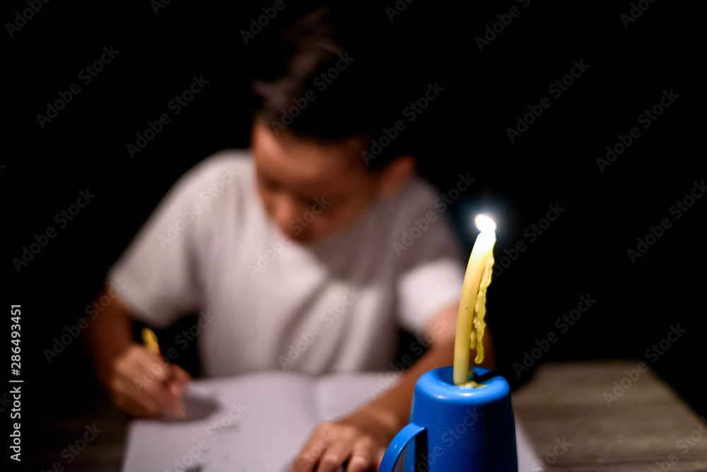 Young boy do home work under candle light Young boy do home work under candle light