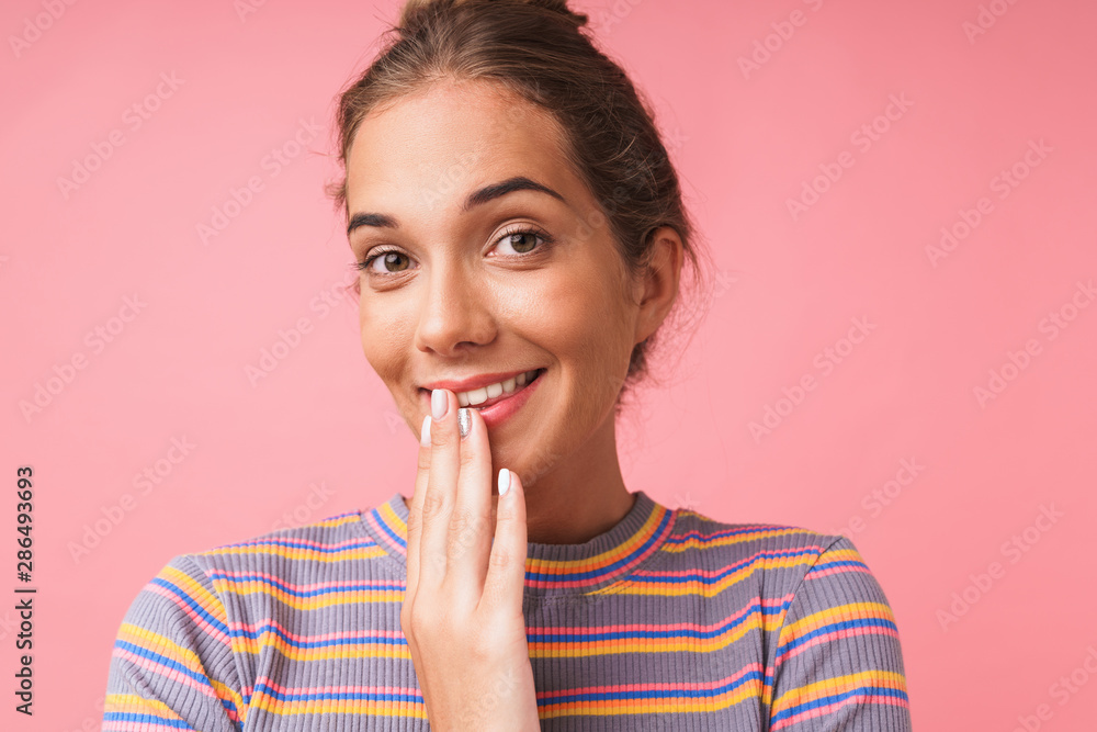 Image closeup of happy beautiful woman dressed in colorful clothes smiling at camera and covering her mouth Image closeup of happy beautiful woman dressed in colorful clothes smiling at camera and covering her mouth