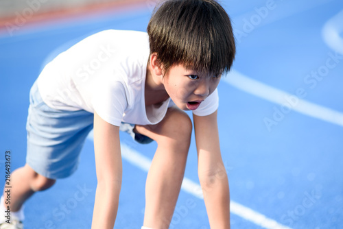 Young boy running on blue track