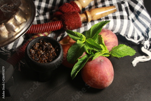 bowl with tobacco for hookah. fruits on a black background. smoking hookah