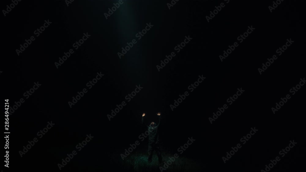 The UFO shines bright light on a man in a dark The UFO shines bright light on a man in a dark