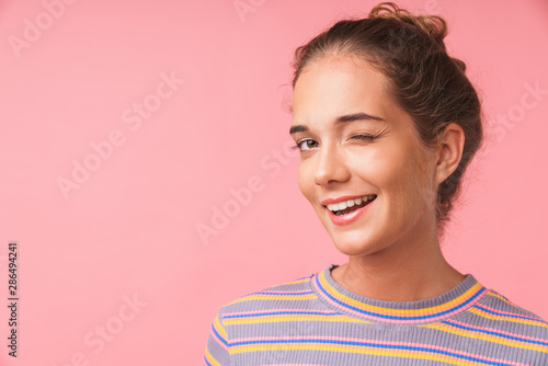 Image closeup of happy beautiful woman dressed in colorful clothes smiling and winking at camera