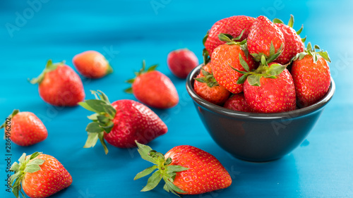 bright printed bowl of fresh strawberries on blue wooden background