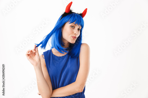 Portrait of seductive woman wearing blue wig and toy devil horns dreaming while looking at camera